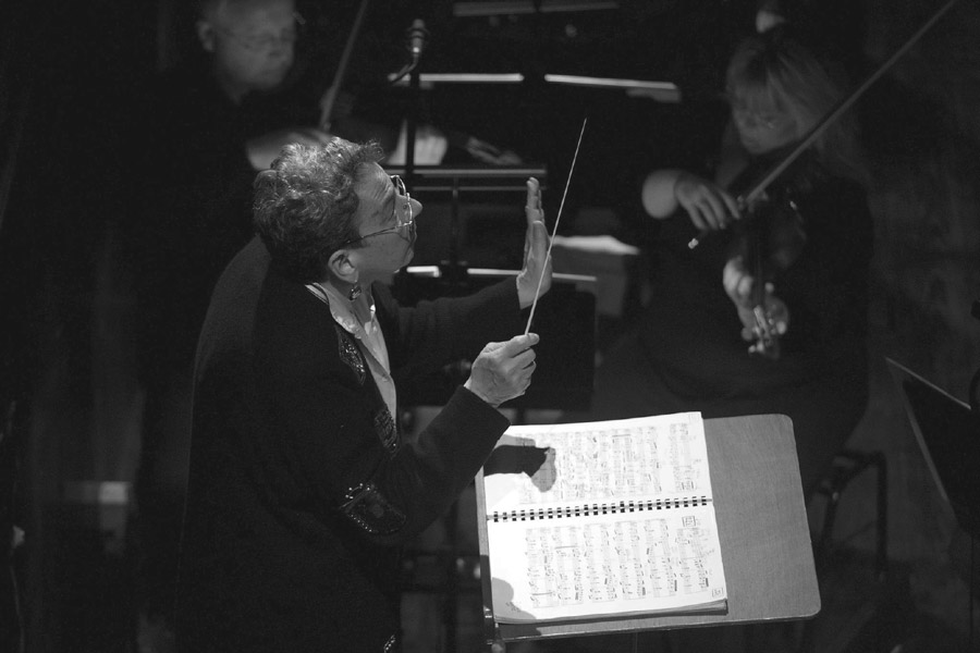 Black and white photograph of Gillian Anderson conducting an orchestra